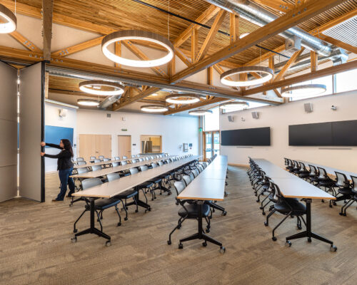 Large conference room with tables and exposed wood trusses at SOESD Phoenix campus