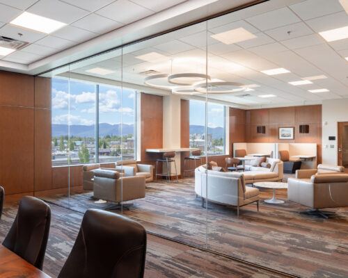 Open office lounge with curved seating, integrated lighting, and large windows