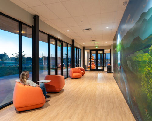 Student commons with lounge seating, landscape mural, and floor-to-ceiling windows